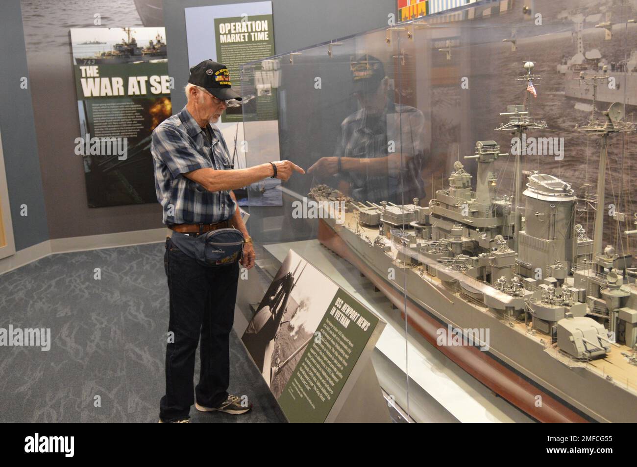 Virgil Greene, che ha servito a bordo della USS Newport News (CA 148) come tecnico della caldaia di seconda Classe, fornisce alcune informazioni riguardo al suo servizio durante una visita al Museo Navale di Hampton Roads. Greene ha servito a bordo di Newport News dal 1969-1973 durante la guerra del Vietnam, ed è raffigurato con un grande modello dell'incrociatore. Il grande modello di nave è in mostra al museo come parte della loro mostra “la guerra dei Temila giorni in mare: Gli Stati Uniti Navy in Vietnam, 1950-1975.” Il museo si trova al secondo piano dell'edificio Nauticus nel centro di Norfolk, Virginia. Foto Stock