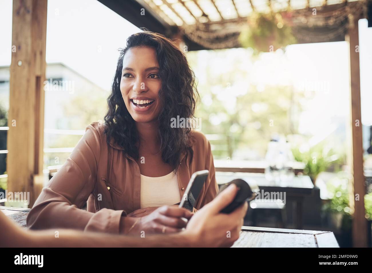 Sono soddisfatto di tutto ciò che è più conveniente. una donna che effettua un pagamento wireless in una caffetteria. Foto Stock