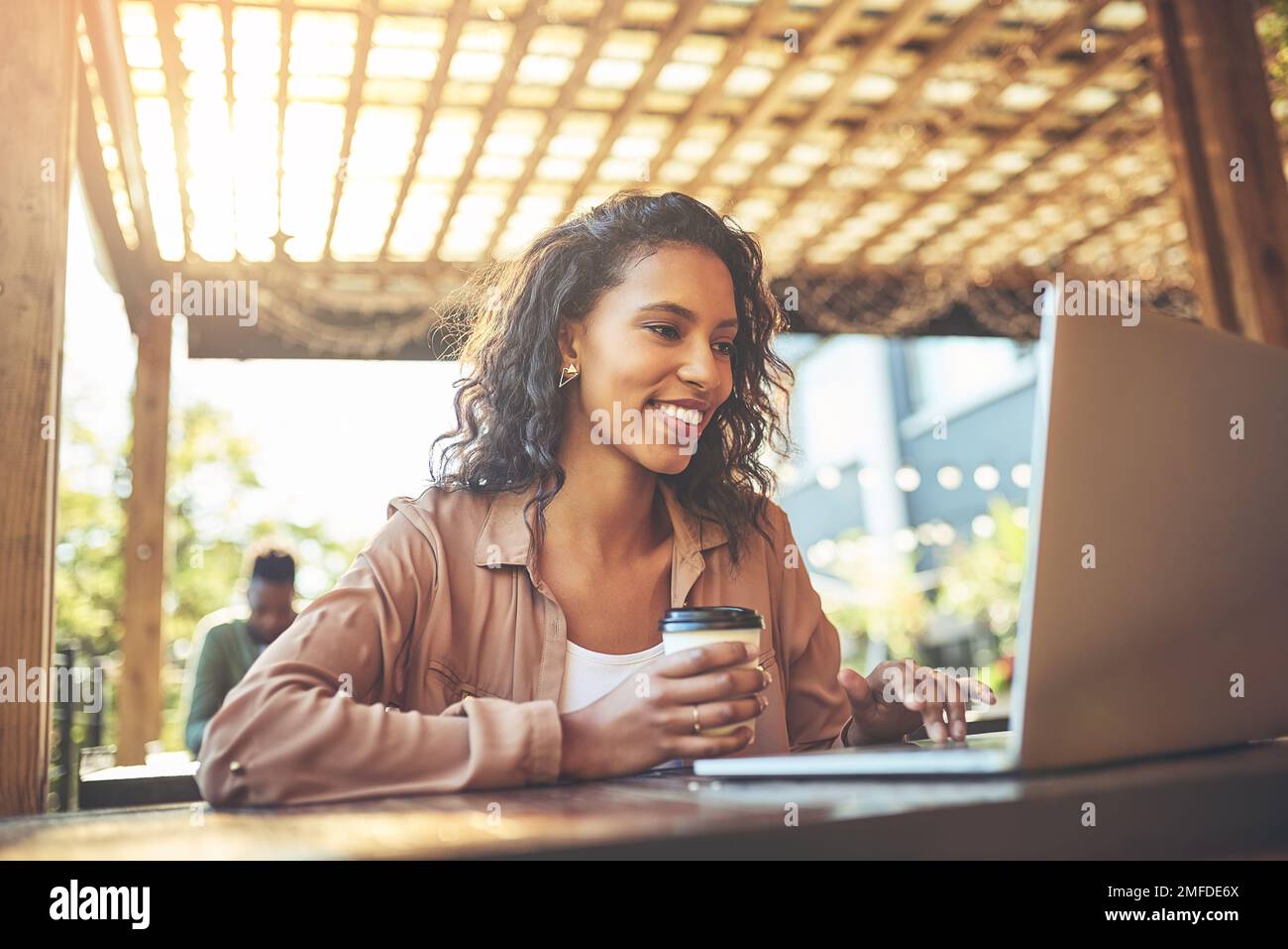 Questo caffè è sicuramente ottenere un posto sul mio blog. una giovane donna che usa un computer portatile in una caffetteria. Foto Stock