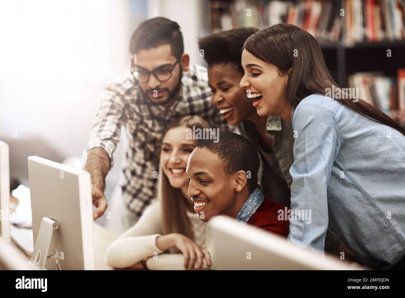 Sforzarsi per successo accademico insieme. un gruppo di studenti universitari che lavorano insieme su un computer nella biblioteca del campus. Foto Stock