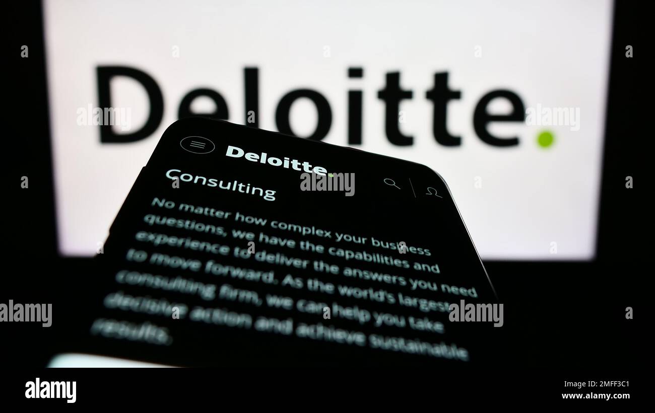 Telefono cellulare con pagina web della società di servizi professionali Deloitte sullo schermo di fronte al logo aziendale. Messa a fuoco in alto a sinistra del display del telefono. Foto Stock