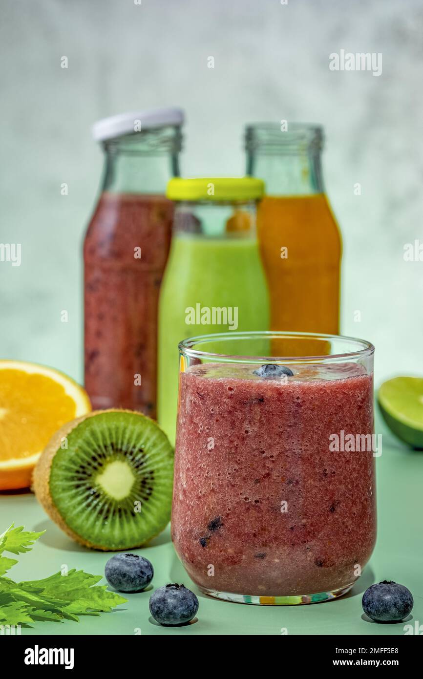 Frullati verdi, arancioni, rossi in bottiglie di vetro e frullati di vetro. Foto Stock