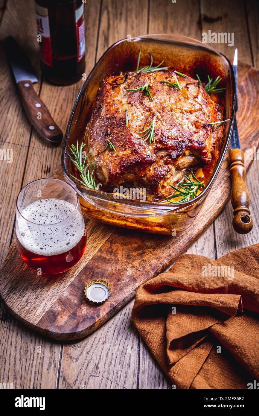 Carne di maiale arrosto con patate, rosmarino e salsa di birra in casseruola Foto Stock