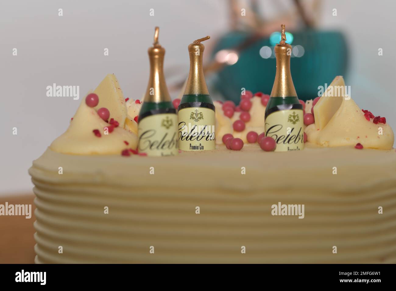 Candele di compleanno a forma di champagne seduti in cima a una torta di compleanno, con le lettere celebrare intorno a loro. un trio di candele Foto Stock