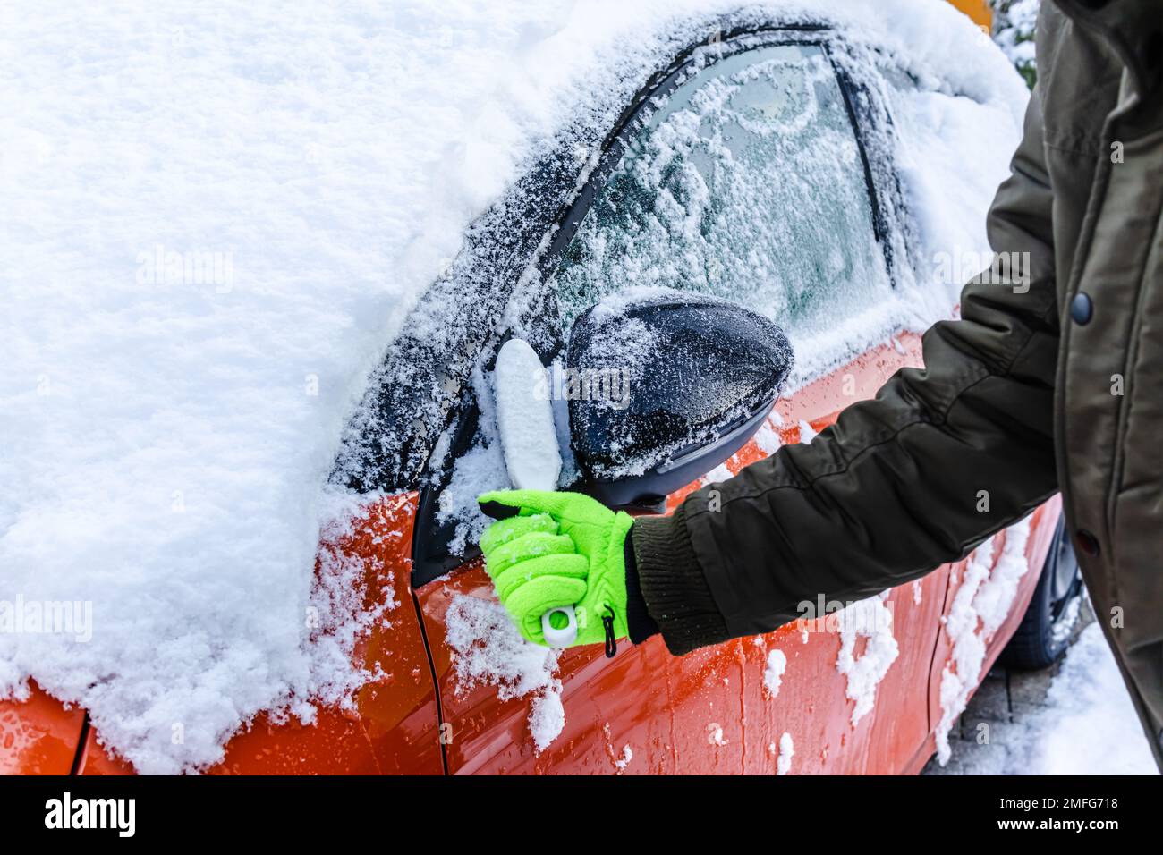 L'adolescente pulisce l'auto dopo una nevicata, rimuovendo la neve e raschiando il ghiaccio Foto Stock