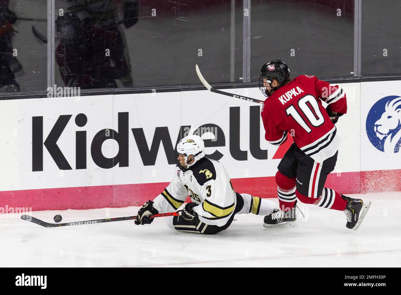 Western Michigan defenseman Michael Joyaux (3) slides on the ice with the puck with St. Cloud State forward Kyler Kupka (10) following during an NCAA hockey game on Tuesday, Dec. 1, 2020, in Omaha, Neb. (AP Photo/John Peterson) Foto Stock