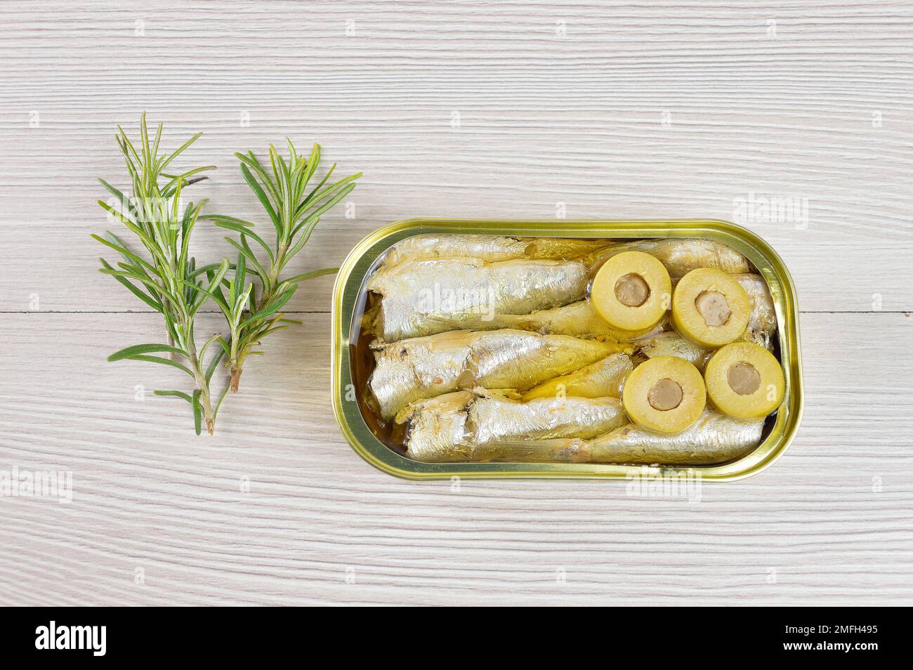 Lattina di sardine su un tavolo in legno rustico Foto Stock