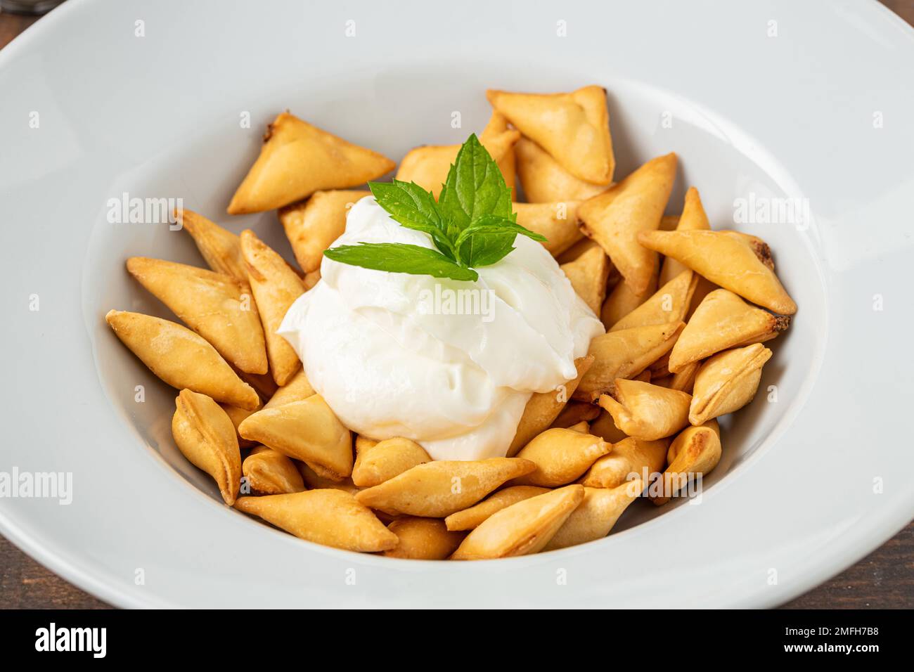 Ravioli turchi fritti e croccanti su un piatto di porcellana bianca Foto Stock