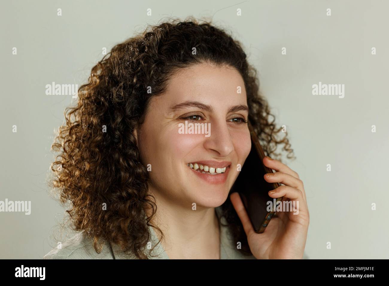Ritratto di una giovane studentessa di razza riccamente mista o di una donna d'affari in una stanza in una biblioteca o in un ufficio che parla al telefono Foto Stock