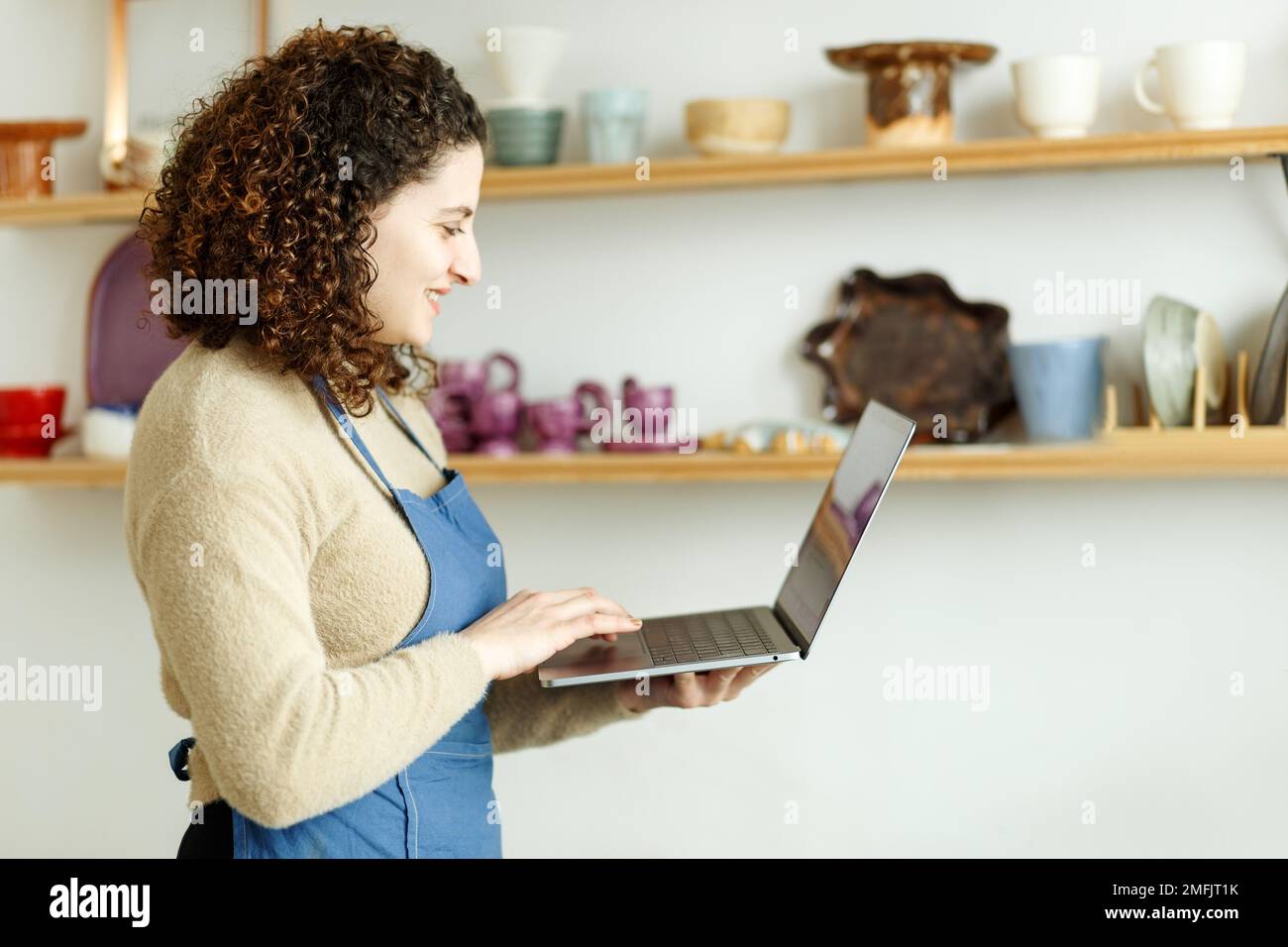 Potter imprenditore utilizzando il laptop in officina, prende ordini online Foto Stock