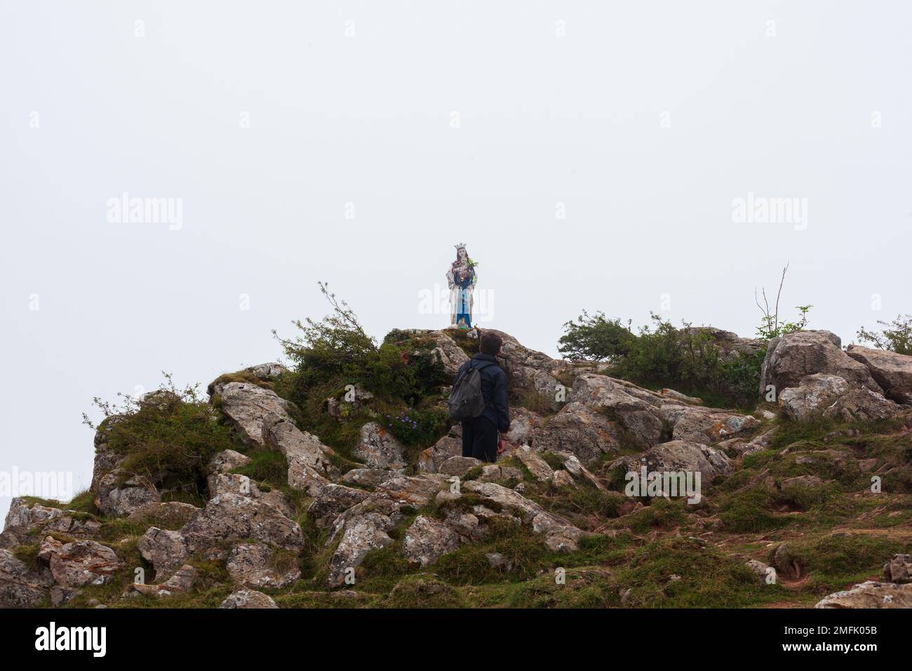 Pellegrino guardando la statua della Vergine Maria in montagna dei Pirenei lungo la strada di San Giacomo Foto Stock