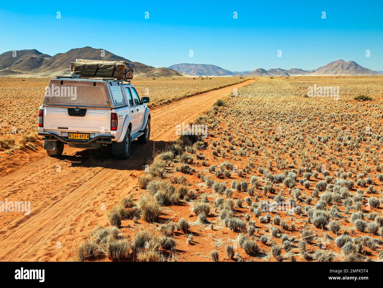 Pick-up che guida su strada deserto verso le montagne Tiras. Tiras, Namib, Namibia - 27 maggio 2022 Foto Stock