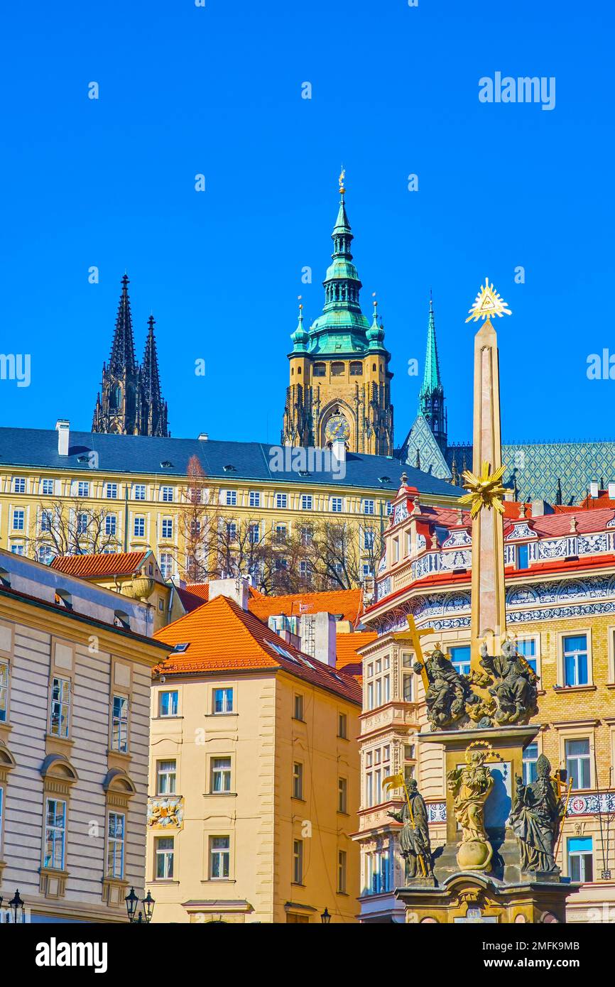 Guglie di St. La Cattedrale di Vito, il Castello di Praga e gli edifici sulla collina attraverso la colonna della Santissima Trinità su Malostranske Namesti, in Cechia Foto Stock