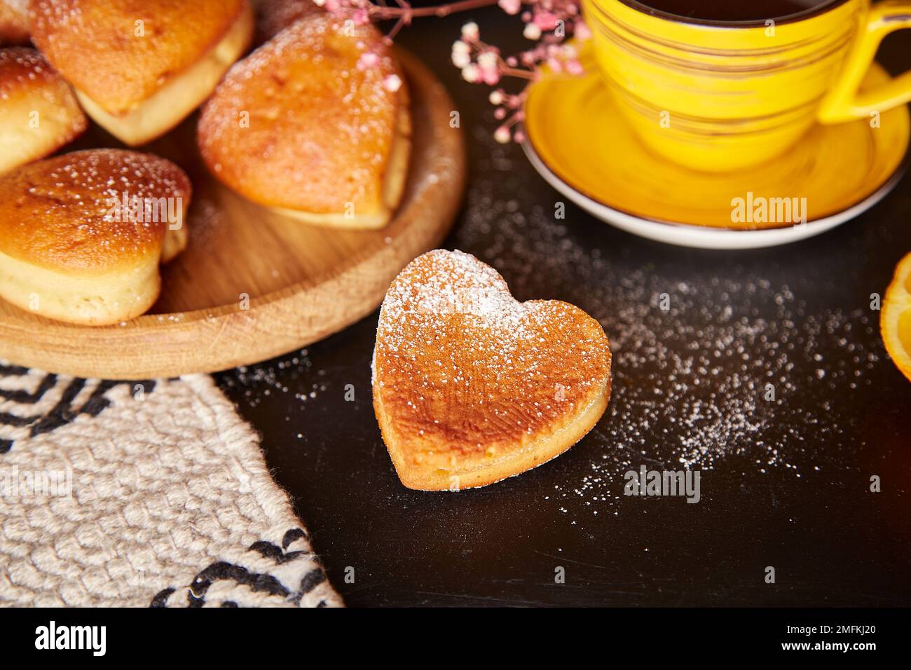 Muffin fatti in casa a forma di cuore con aroma arancione per San Valentino. Tempo del tè, tazze gialle. Foto Stock