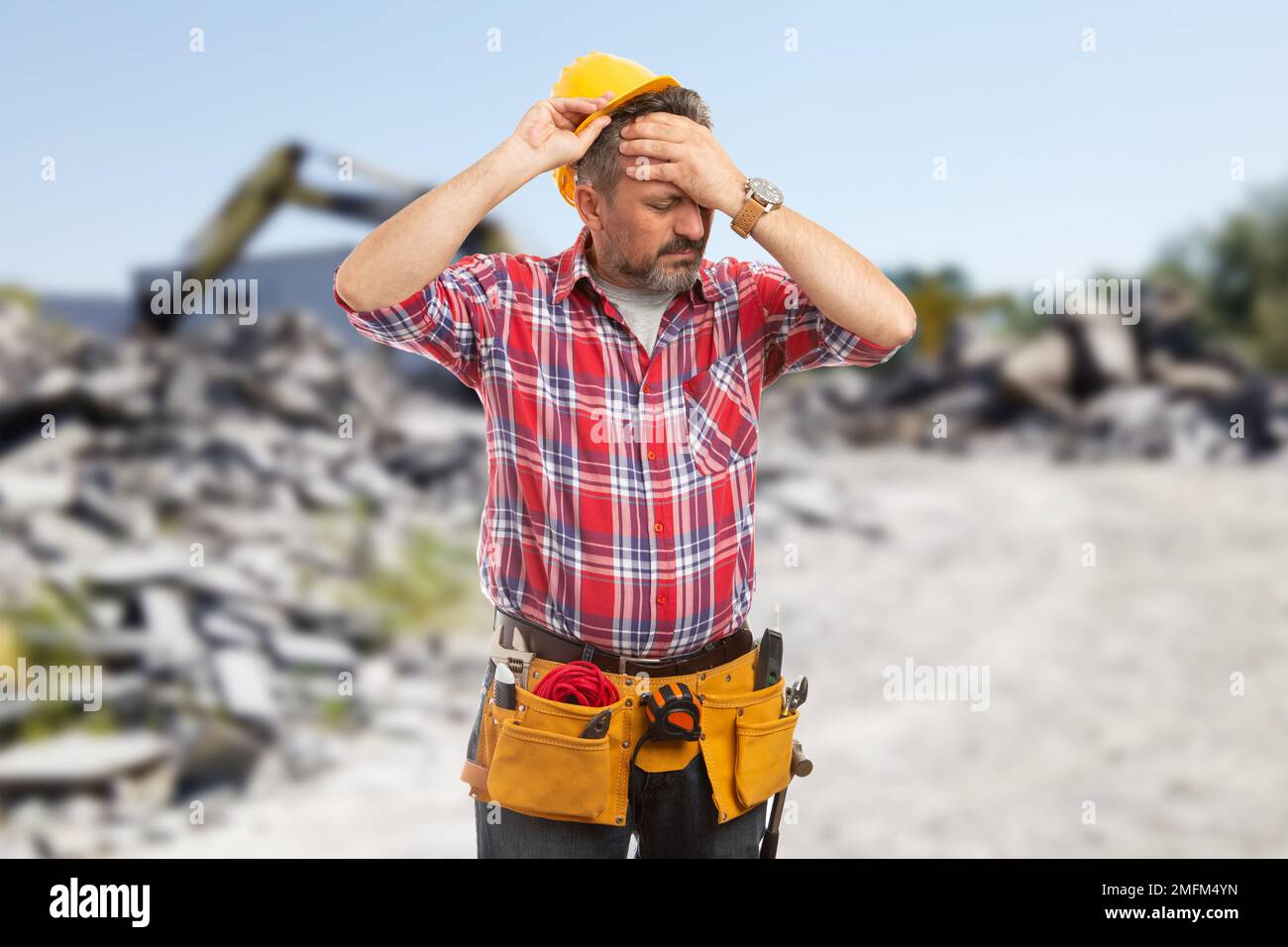 Lavoratore maschio stanco che ha mal di testa e togliere il casco come estenuante concetto di giornata di lavoro Foto Stock