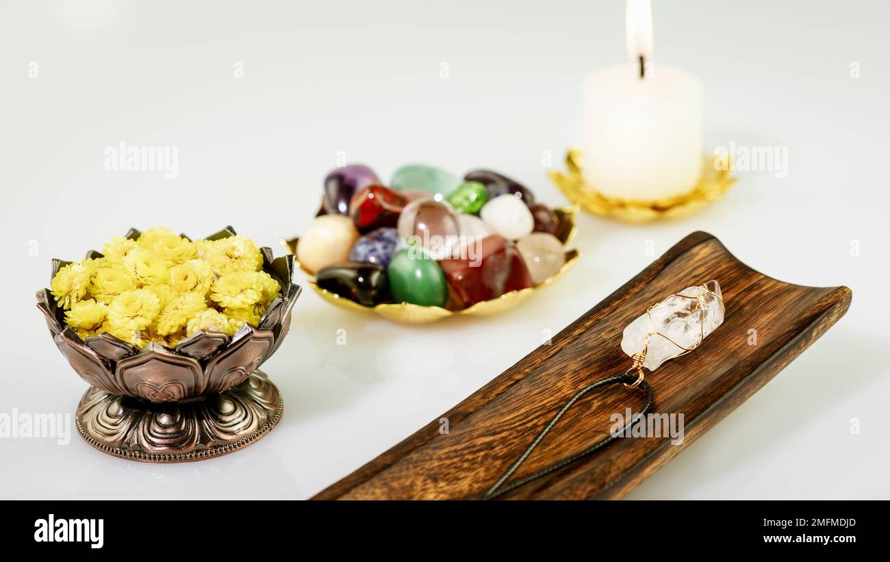 Rituale rilassante con set di pietre a cristalli, candela e fiori secchi su sfondo bianco. Pratica spirituale esoterica, Rituale Cristallo guarigione, relax Chakr Foto Stock