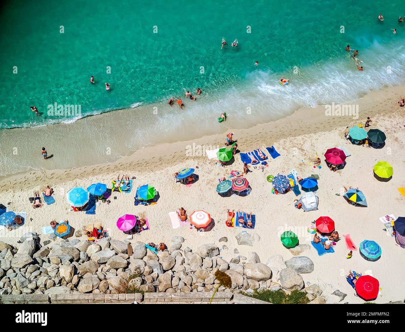 Spiagge italiane della Calabria visto dall'alto, i turisti visti riposare sotto ombrelloni colorati Foto Stock