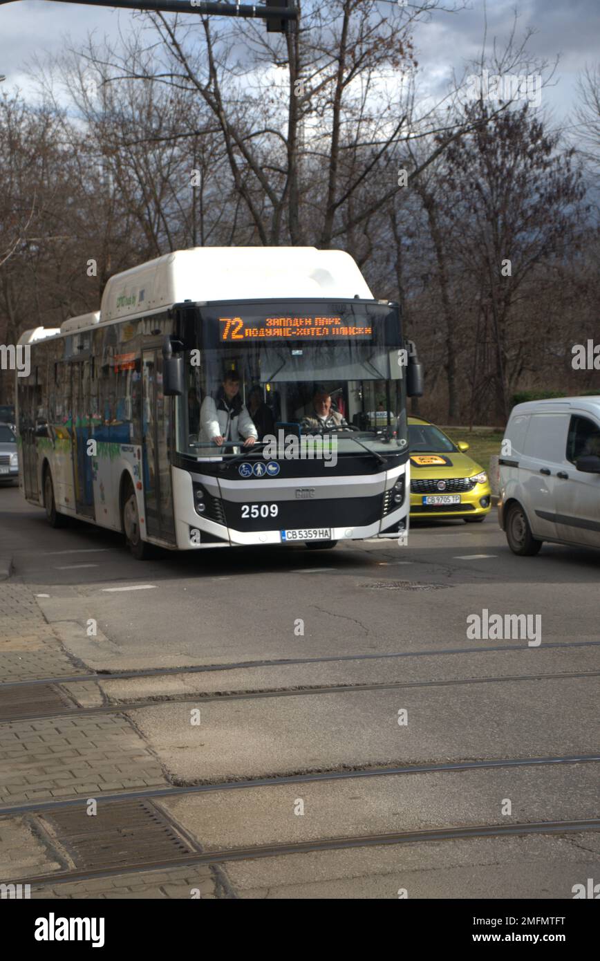 Uno scatto verticale di un autobus bianco che passa per le strade della città di giorno, scena stradale Foto Stock