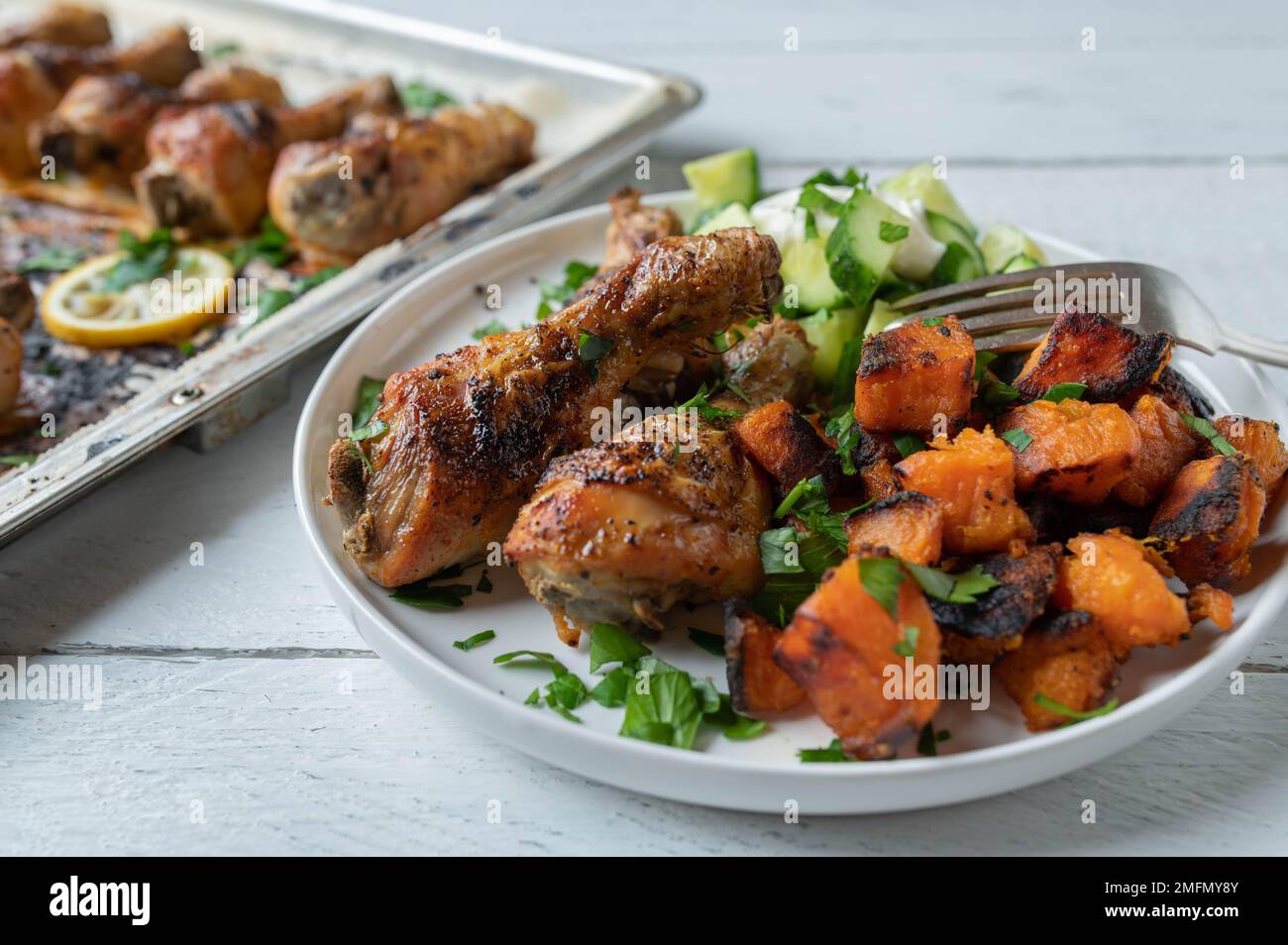 Bastoncini di pollo con patate dolci arrostite e insalata di cetrioli su un piatto Foto Stock