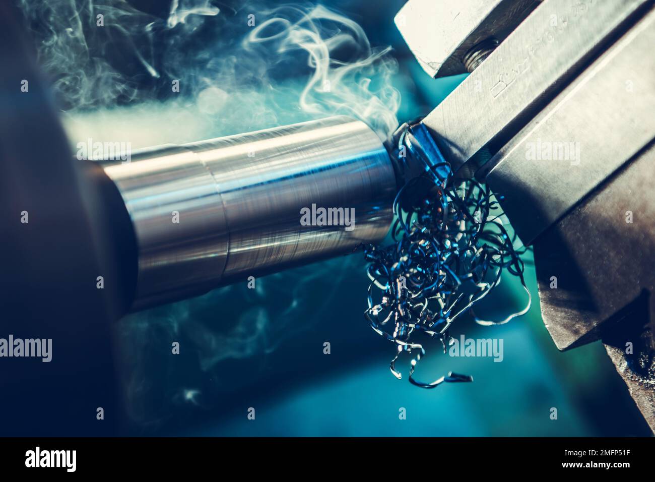 Lavorazione di elementi metallici in tornio macchina primo piano. Calore estremo e rilascio di fumo durante il processo. Tema macchine industriali. Foto Stock