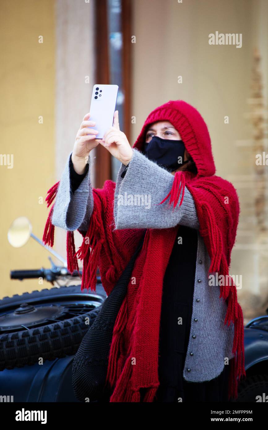 Donna con abiti invernali tradizionali e maschera protettiva cammina per le strade di Lisbona Foto Stock