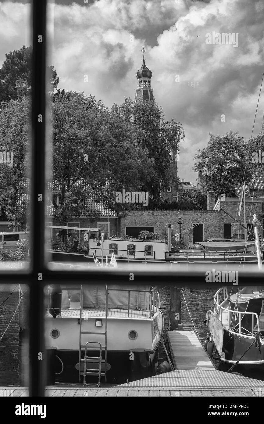 Enkhuizen, Paesi Bassi - Agosto 18,2021: Vista dalla finestra al porto e barche a vela ormeggiate. Sullo sfondo, la cupola della chiesa e stunniti Foto Stock