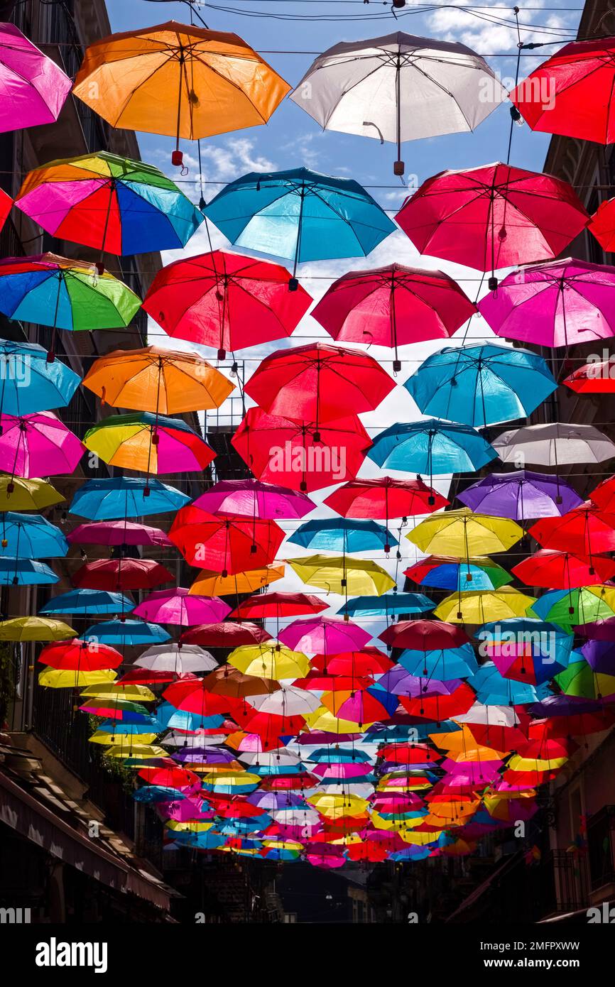 Ombrelloni colorati appendono decorativamente in uno dei vicoli del centro storico di Catania. Foto Stock