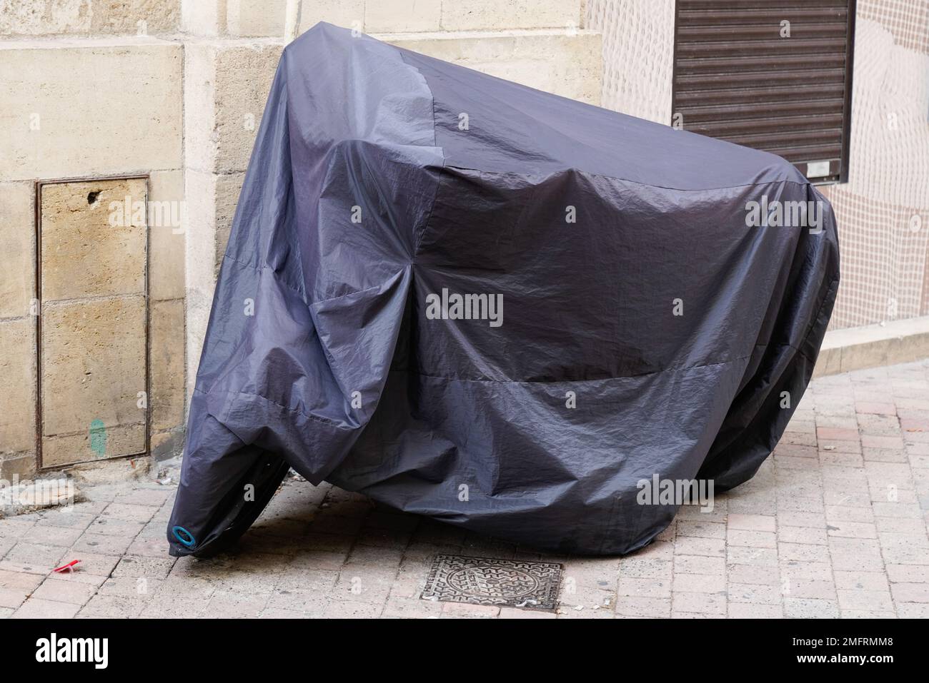 copricicletta in plastica protetta in moto da strada con giacca in telone scuro Foto Stock