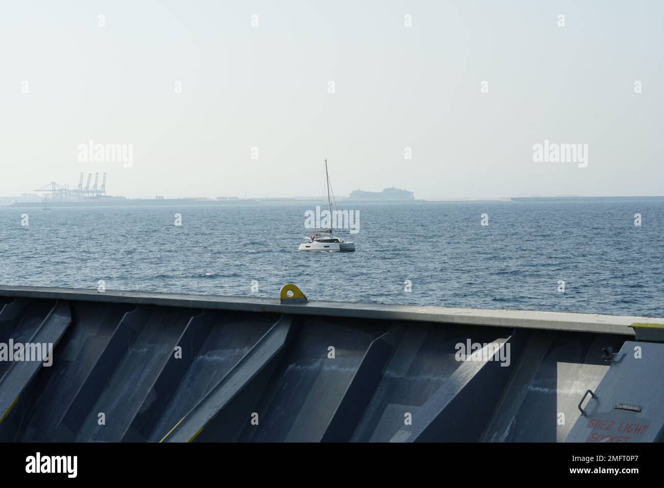 Vista dalla prua o dall'ormeggio delle navi, stazione di manovra della nave container su un catamarano da diporto a vela. Foto Stock