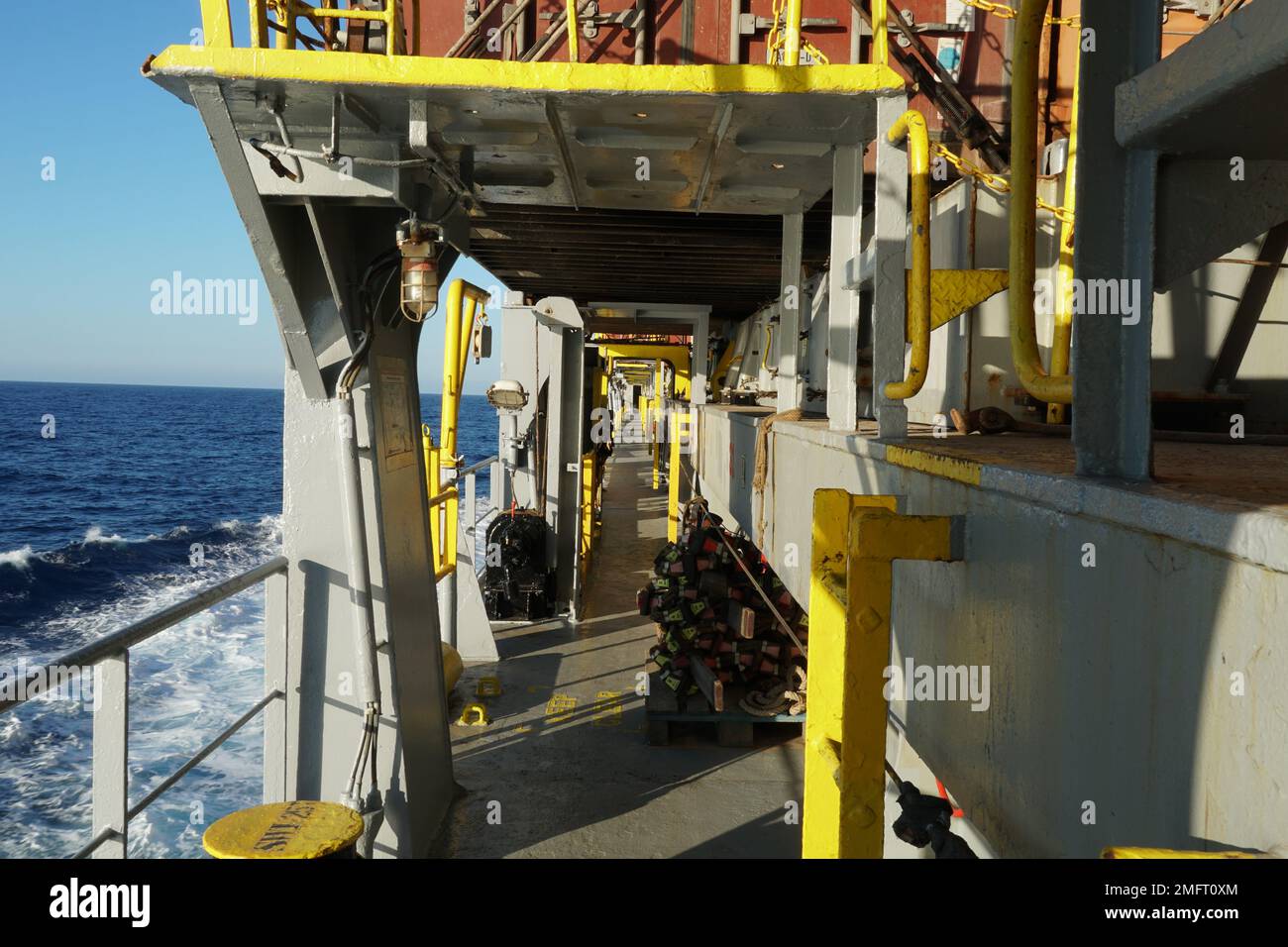 Vista sul ponte principale e sulle piattaforme di ancoraggio della nave portacontainer dipinta di grigio con segni gialli di ostacoli pericolosi. Foto Stock