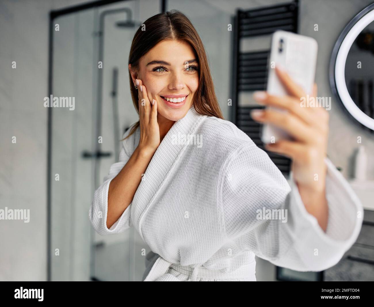 positivo giovane donna accappatoio presa selfie Foto Stock