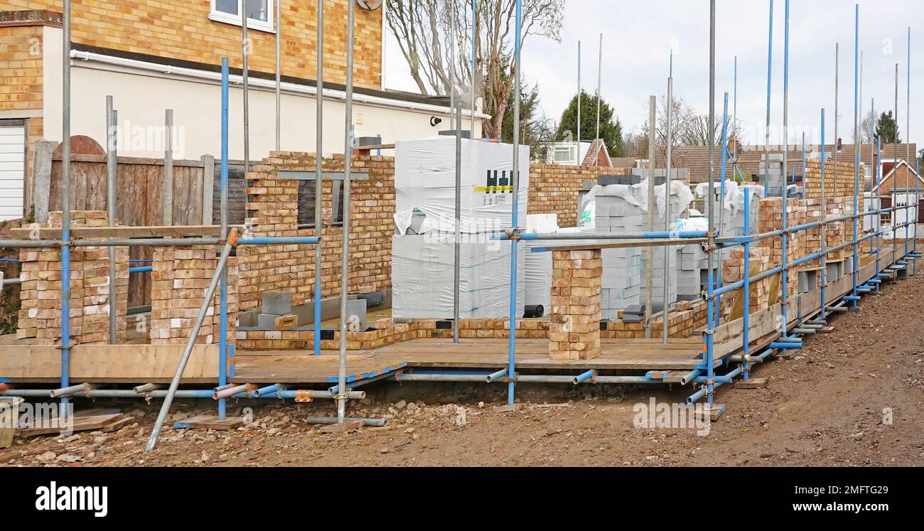 Vista frontale laterale d'angolo nuove pareti in mattoni e blocchi in costruzione per impalcature di proprietà residenziali staccate eretto materiali da costruzione impilati Inghilterra UK Foto Stock