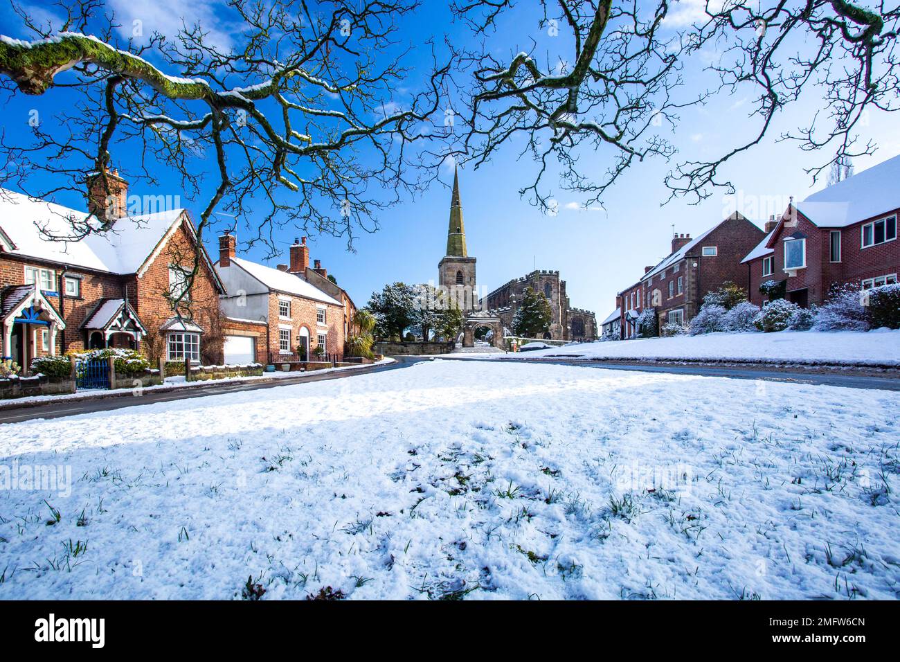 Chiesa di Santa Maria ad Astbury vicino a Congleton Cheshire Inghilterra con i cottage sul verde villaggio coperto di neve in inverno Foto Stock