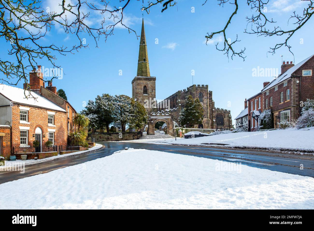 Chiesa di Santa Maria ad Astbury vicino a Congleton Cheshire Inghilterra con i cottage sul verde villaggio coperto di neve in inverno Foto Stock