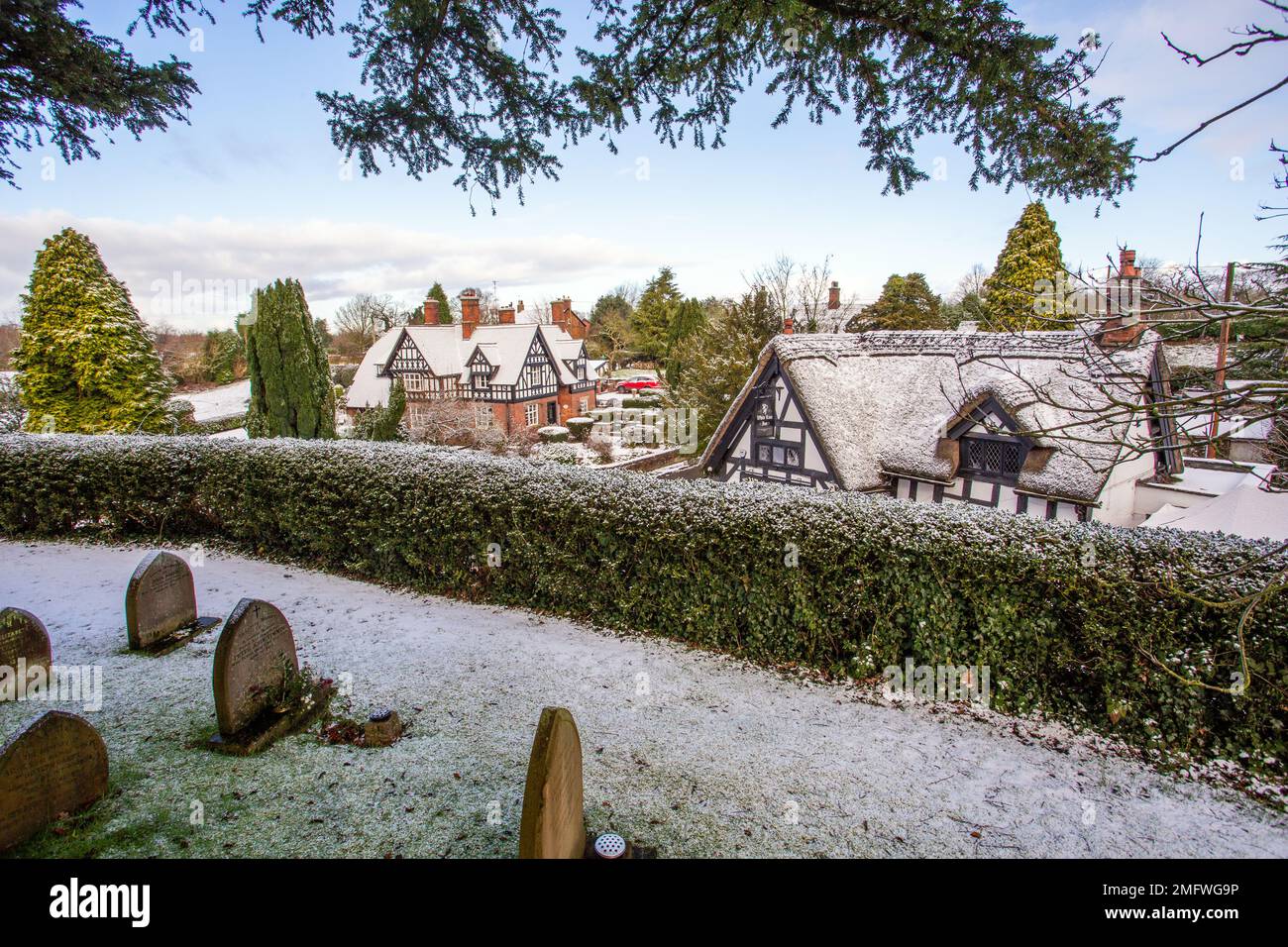 Coperta di neve in bianco e nero la metà case con travi di legno nel pittoresco villaggio di Cheshire di Barthomley England Regno Unito durante il periodo invernale Foto Stock