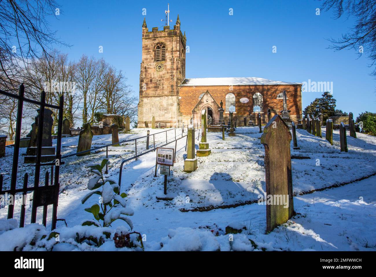Vista della Chiesa di tutti i Santi nel villaggio di Cheshire di Church Lawton dopo una caduta di neve invernale Foto Stock