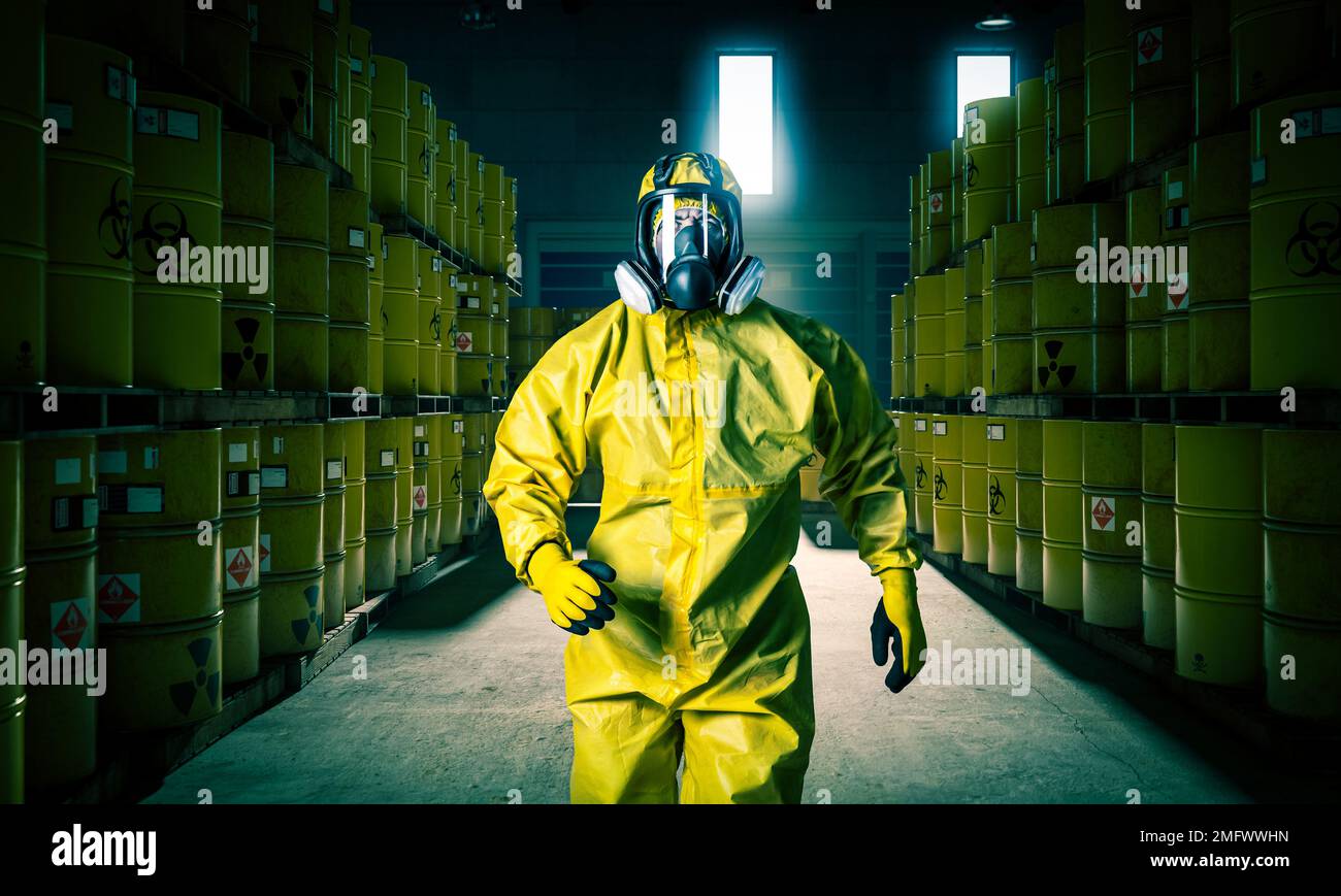 L'uomo in maschera e gli indumenti protettivi gialli camminano all'interno di un sito di stoccaggio delle scorie. Foto Stock