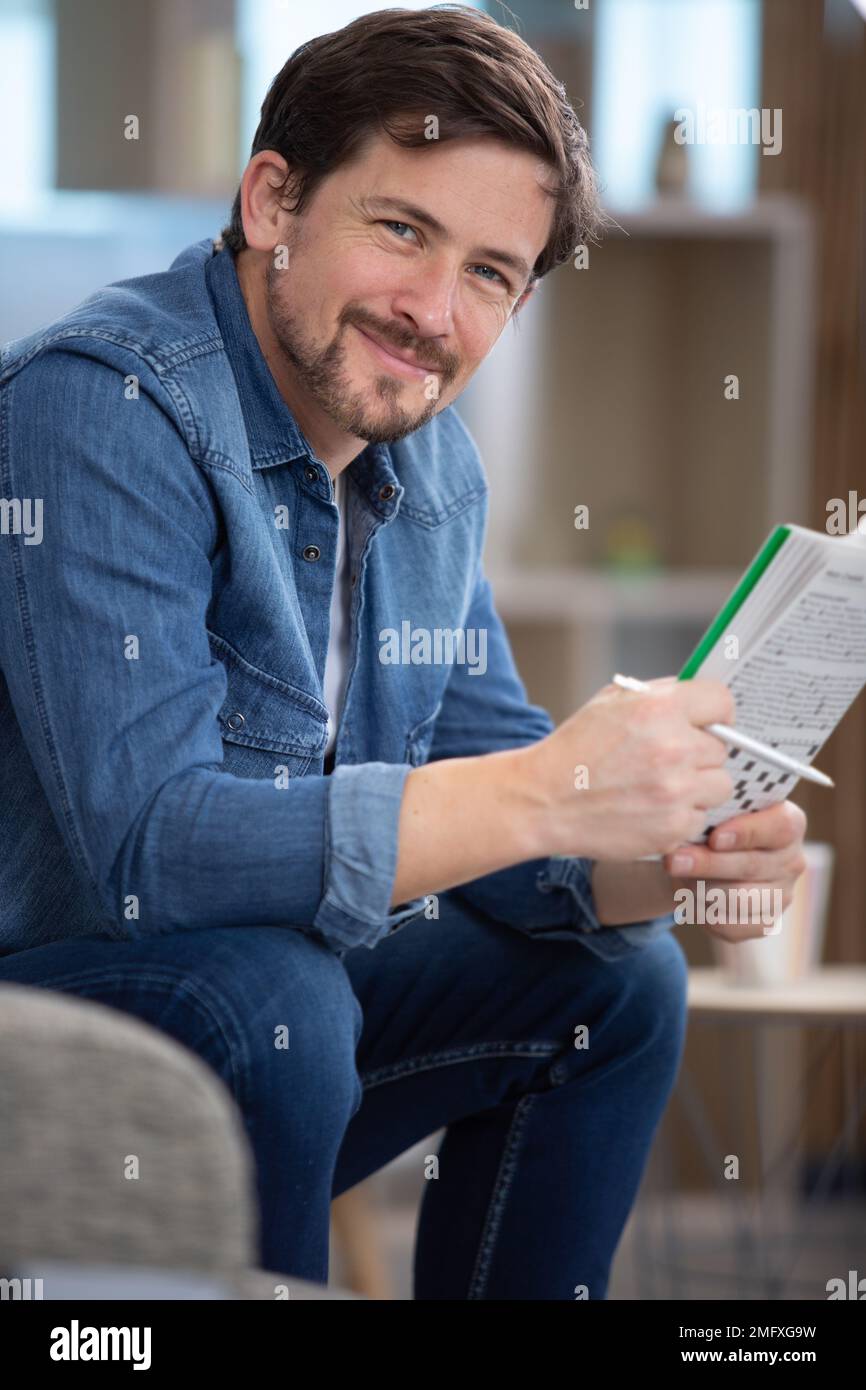 giovane uomo seduto facendo un puzzle crossword Foto Stock
