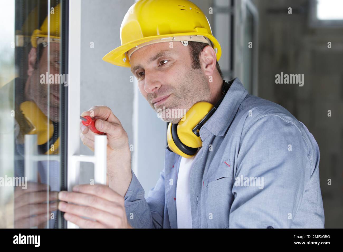 il lavoratore senior sta montando una finestra in pvc Foto Stock