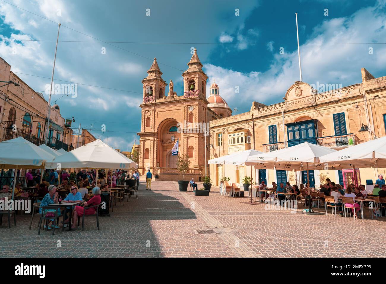Marsaxlokk, Malta, Europa - 22 ottobre 2022: Turisti che si godono la vacanza sulle terrazze nella piazza centrale della città di Marsaxlokk e la tradizione Foto Stock
