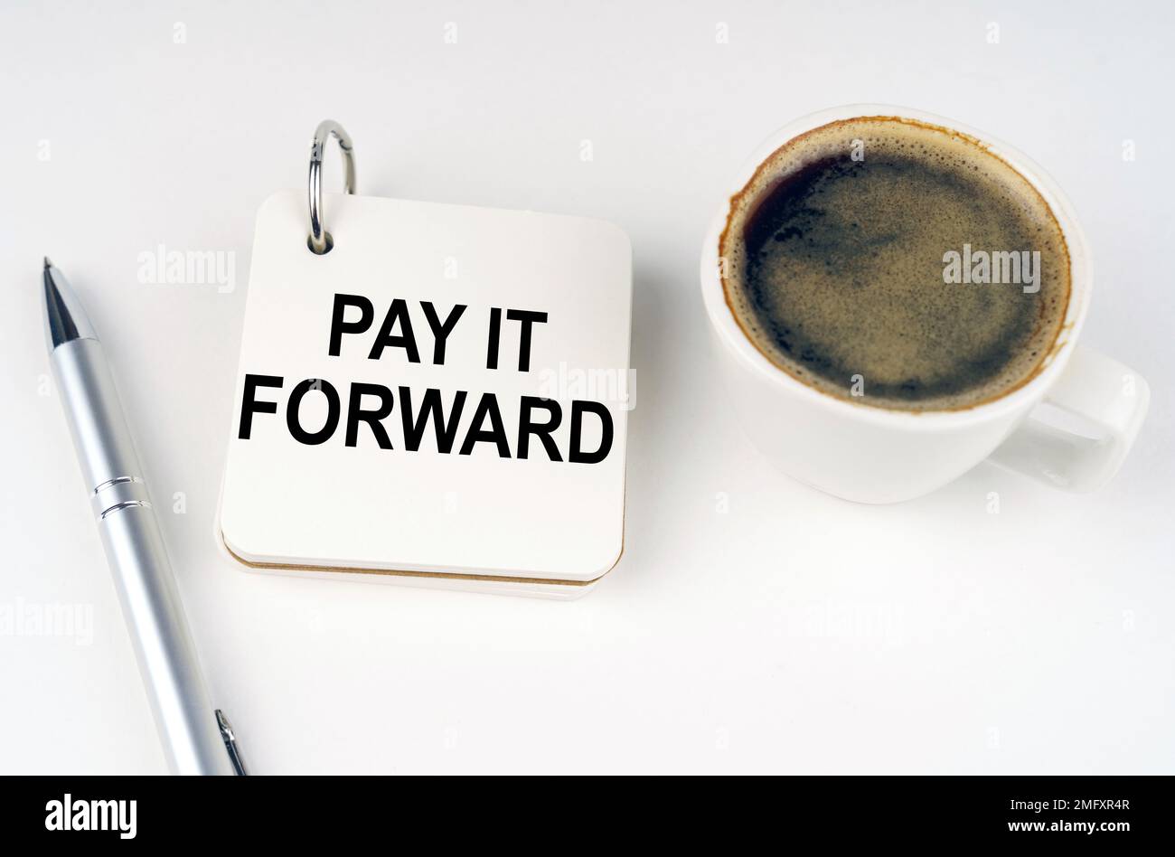 Concetto aziendale. Su una superficie bianca, una tazza di caffè, una penna e un blocco note con l'iscrizione - PAGALO IN AVANTI Foto Stock