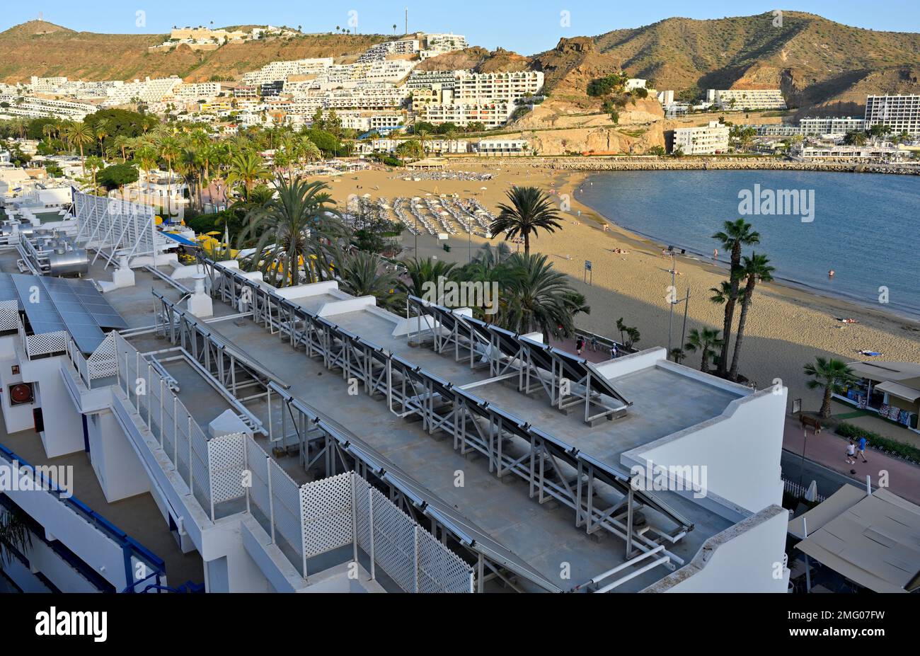 Pannelli solari termici sul tetto dell'hotel che si affaccia sulla spiaggia sabbiosa di Playa de Puerto Rico e sul lungomare, Arguineguín, Gran Canaria Foto Stock