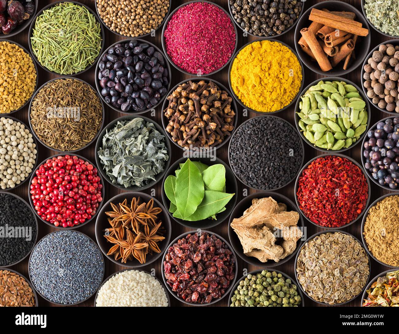 Spezie ed erbe fresche per il cibo. Condimenti colorati come sfondo, vista dall'alto. i condimenti del lotto in tazze, sul tavolo Foto Stock