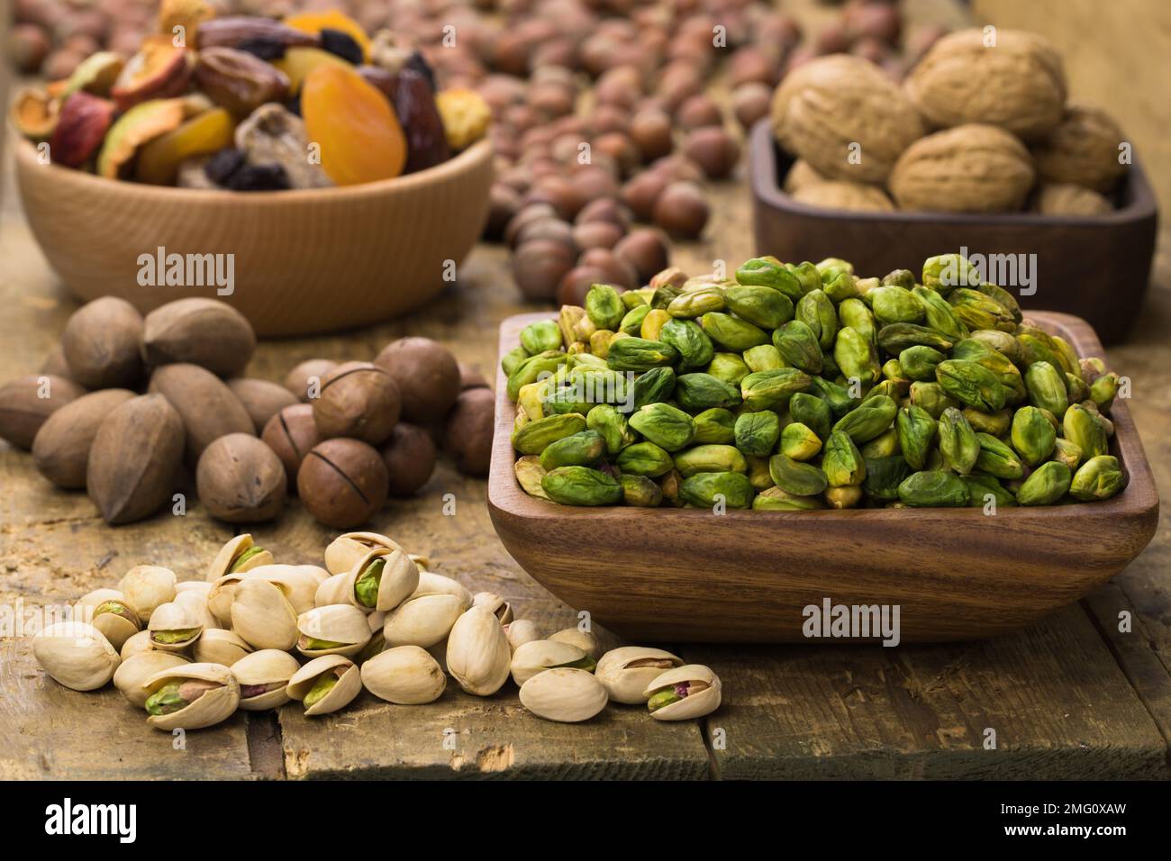 noci di pistacchi pelate verde in ciotola su tavola di legno. Alimenti utili per vegetariani e vegani. Foto Stock