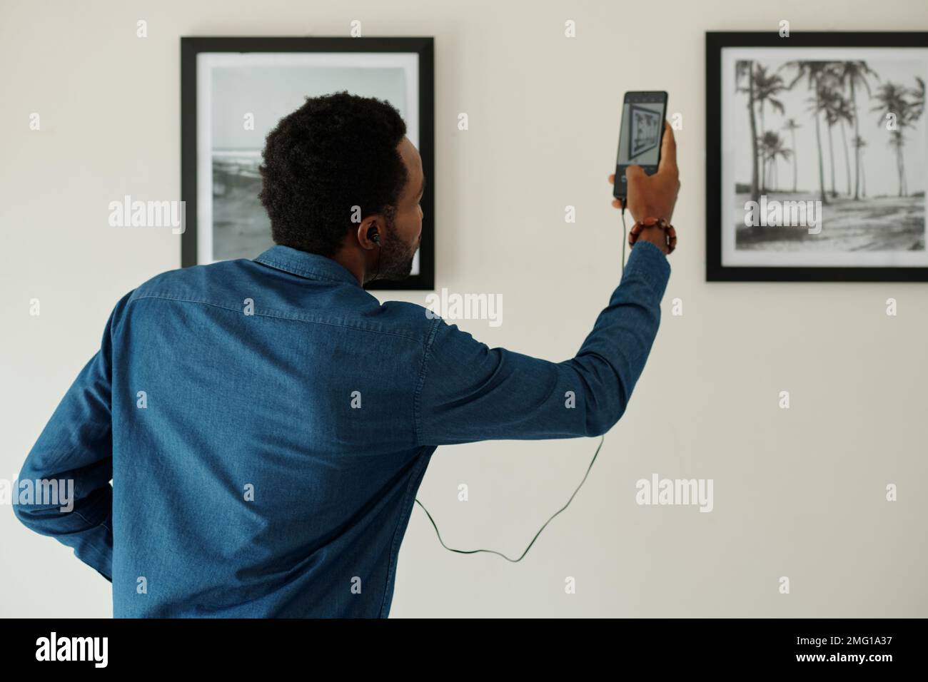 Uomo che scansiona il codice qr sulla fotografia nella galleria d'arte per ascoltare l'audioguida Foto Stock