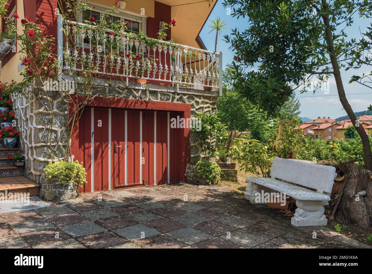 Cortile interno di una casa residenziale piena di piante, fiori e una panca di pietra bianca nella città di Arredondo, Cantabria, Spagna, Europa Foto Stock