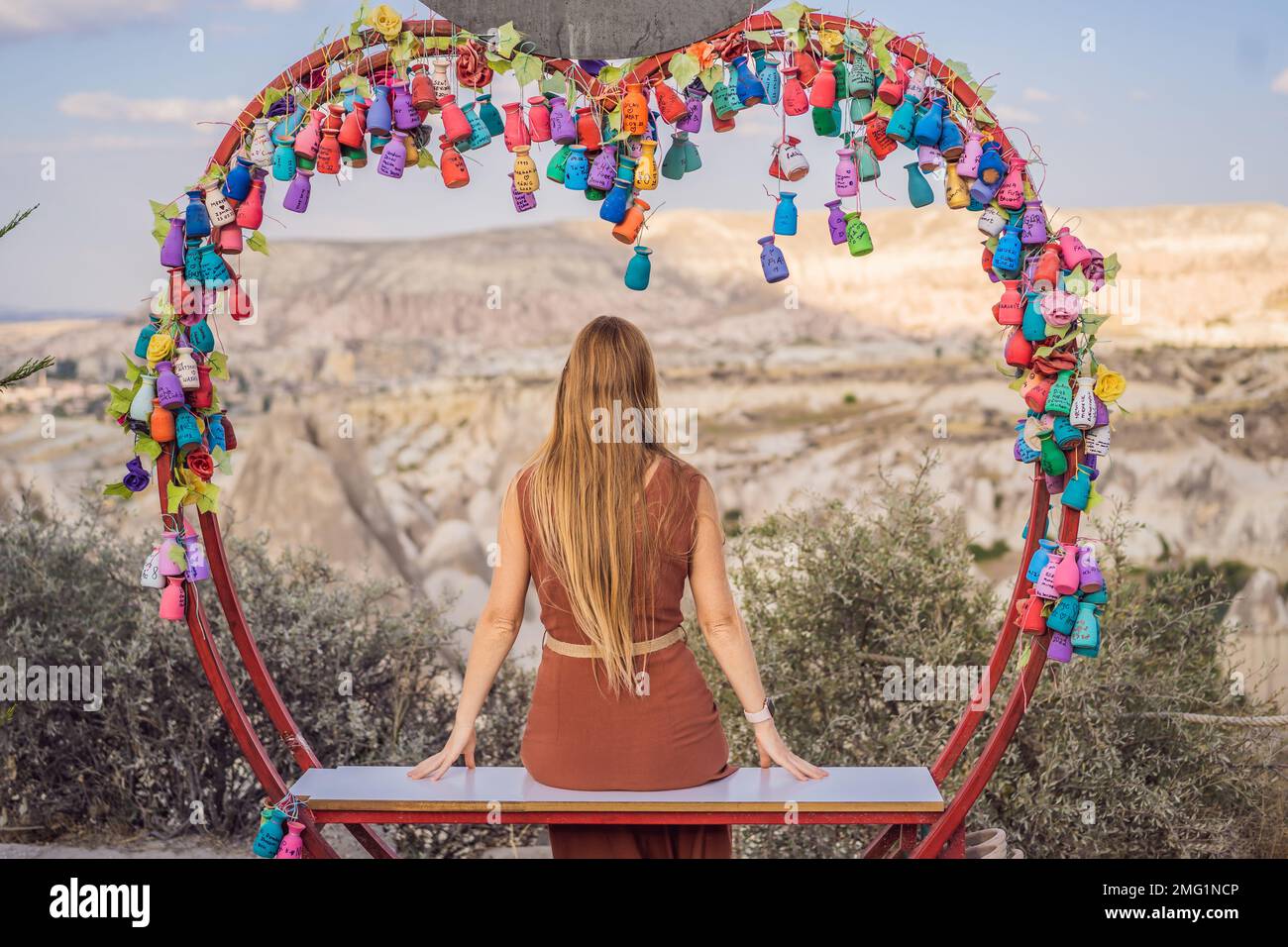 Giovane donna che esplora la valle con formazioni rocciose e grotte delle fate vicino a Goreme in Cappadocia Turchia. Albero dei desideri. Piccole caraffe multicolore con Foto Stock