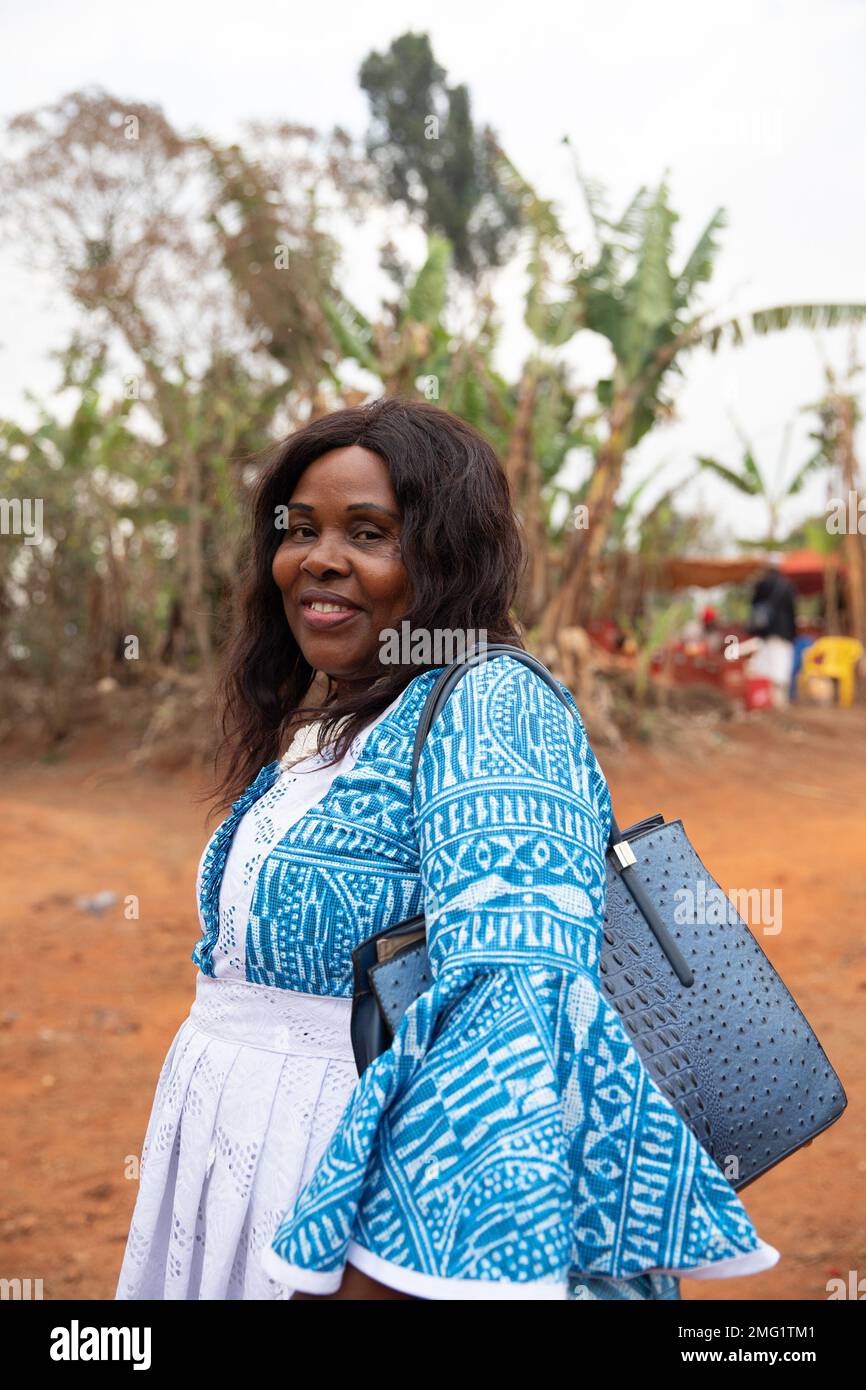 Donna africana sorridente vestita con abiti tradizionali e dotata di borsa, foto verticale Foto Stock