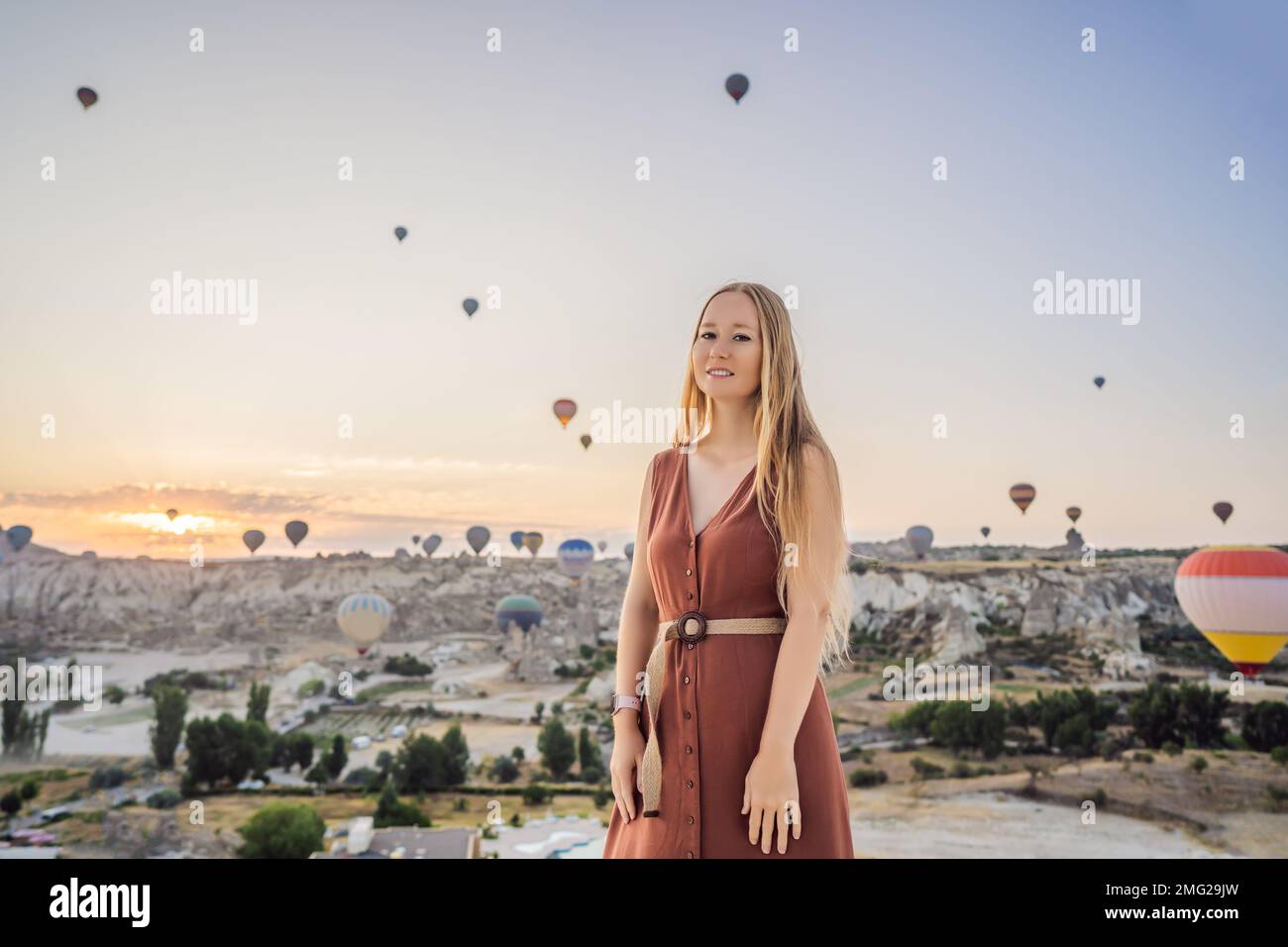 Donna turistica che guarda mongolfiere in Cappadocia, Turchia. Buon viaggio in Turchia concetto. Donna in cima a una montagna che gode di una vista meravigliosa Foto Stock