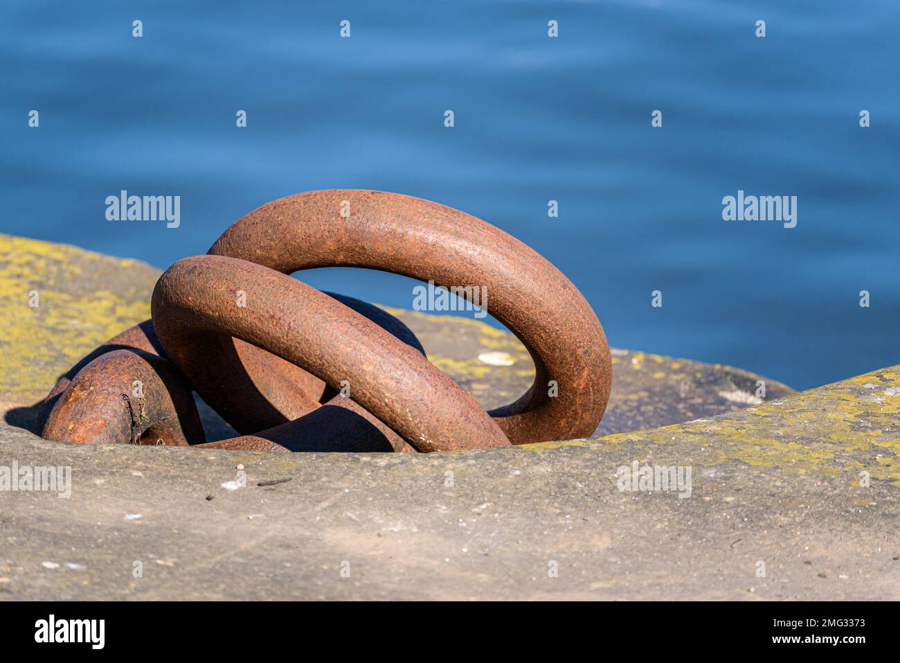 Primo piano di arrugginiti anelli di ormeggio su una banchina in un porto fluviale Foto Stock